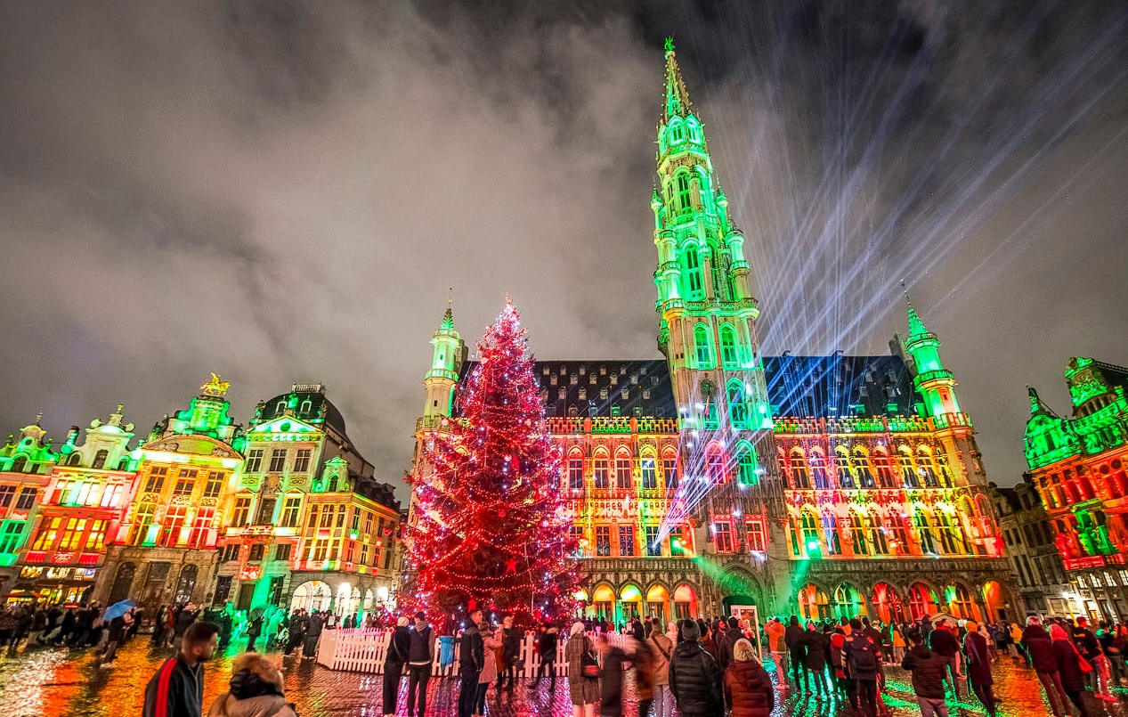 Chalets décorés du marché de Noël de Bruxelles sur la Grand-Place, illuminée de mille feux, avec des visiteurs profitant de l’atmosphère festive